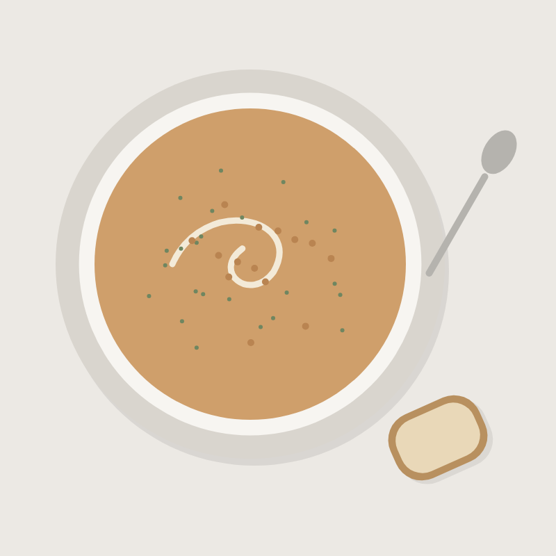 Bowl of roasted carrot soup with a swirl of cream, beside a slice of bread